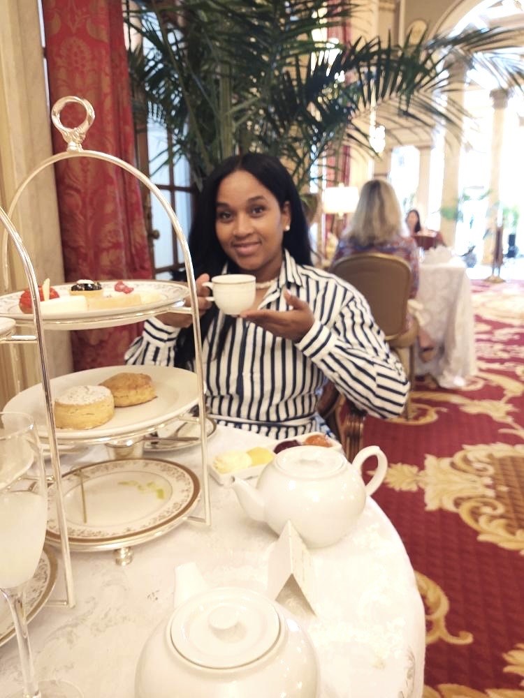 A woman sitting at a table with cupcakes and tea.