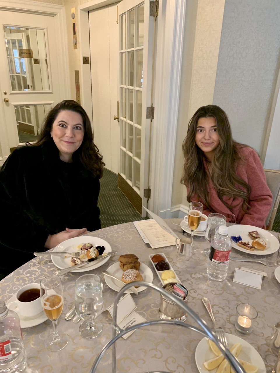 Two women sitting at a table with plates of food.